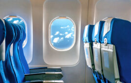 Looking out passenger window of an airplane with blue seats.